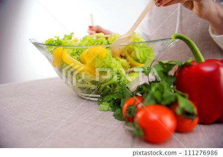 Balanced diet, healthy food concept on wooden board. View from above vegetable salad from a glass plate with a wooden spatula stir vegetables Balanced diet, healthy food concept on wooden board. View from above vegetable salad from a glass plate with a wooden spatula stir vegetables 111276986