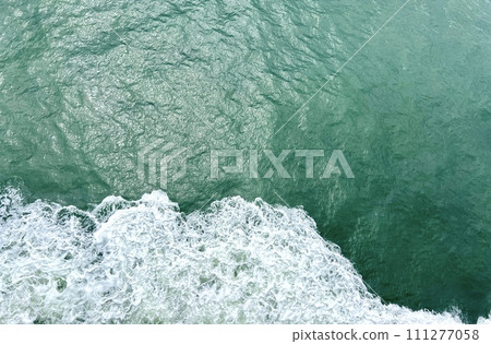 waves of the sea or ocean from under the ship floating quickly on the waves puffs of water with white foam the water itself Emerald Green very beautiful background for any travel text travel agency 111277058