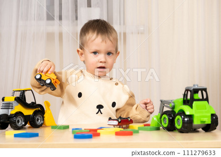 Little cute boy playing with toys while sitting at table Little cute boy playing with toys while sitting at table 111279633