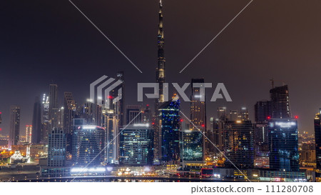 Aerial view to Dubai Business Bay and Downtown with the various skyscrapers and towers all night timelapse 111280708