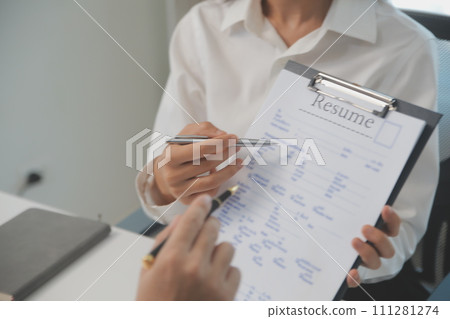 Close up view of job interview in office, focus on resume writing tips, employer reviewing good cv of prepared skilled applicant, recruiter considering application, hr manager making hiring decision 111281274
