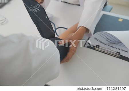 Male doctor uses a blood pressure monitor to check the body pressure and pulse of the patients who come to the hospital for check-ups, Medical treatment and health care concept. Male doctor uses a blood pressure monitor to check the body pressure and pulse of the patients who come to the hospital for check-ups, Medical treatment and health care concept. 111281297