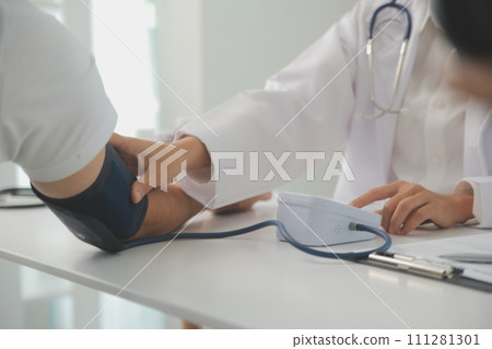 Male doctor uses a blood pressure monitor to check the body pressure and pulse of the patients who come to the hospital for check-ups, Medical treatment and health care concept. 111281301