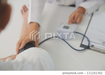 Male doctor uses a blood pressure monitor to check the body pressure and pulse of the patients who come to the hospital for check-ups, Medical treatment and health care concept. 111281302