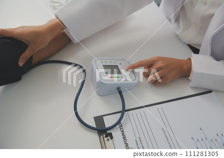 Male doctor uses a blood pressure monitor to check the body pressure and pulse of the patients who come to the hospital for check-ups, Medical treatment and health care concept. Male doctor uses a blood pressure monitor to check the body pressure and pulse of the patients who come to the hospital for check-ups, Medical treatment and health care concept. 111281305