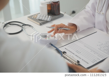 Male doctor uses a blood pressure monitor to check the body pressure and pulse of the patients who come to the hospital for check-ups, Medical treatment and health care concept. Male doctor uses a blood pressure monitor to check the body pressure and pulse of the patients who come to the hospital for check-ups, Medical treatment and health care concept. 111281323