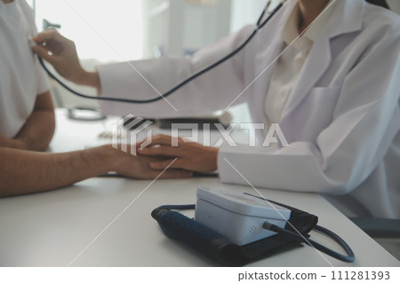 Young doctor is using a stethoscope listen to the heartbeat of the patient. Shot of a female doctor giving a male patient a check up Young doctor is using a stethoscope listen to the heartbeat of the patient. Shot of a female doctor giving a male patient a check up 111281393