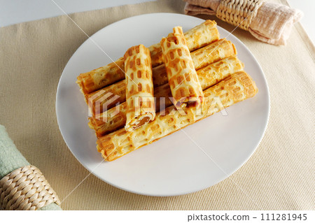 Mouthwatering stack of delicious golden waffles sits atop a pristine white plate placed elegantly on a table. Mouthwatering stack of delicious golden waffles sits atop a pristine white plate placed elegantly on a table. 111281945