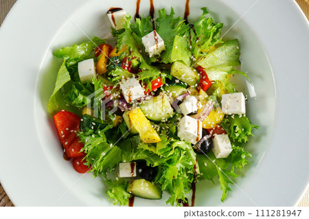A beautifully presented salad, generously dressed, arranged on a pristine white plate. A beautifully presented salad, generously dressed, arranged on a pristine white plate. 111281947