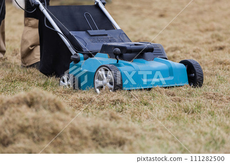 Scarifying lawn with scarifier, Man gardener scarifies the lawn and removal of old grass 111282500