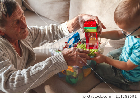 Elderly grandpa or grandfather plays with his little grandson Elderly grandpa or grandfather plays with his little grandson 111282591