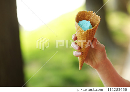 Female hand holding wafer cone with blue ice cream. Close up, High resolution product. blue ice cream in hand. 111283666