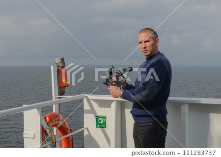 Seaman with sextant on navigational bridge 111283737
