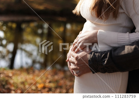Family day. Stylish unrecognisable marriage pregnant couple waiting for baby. Man is hugging and touching woman belly outdoors. World IVF Day. Pregnancy, parenthood, motherhood, love, family concept. Family day. Stylish unrecognisable marriage pregnant couple waiting for baby. Man is hugging and touching woman belly outdoors. World IVF Day. Pregnancy, parenthood, motherhood, love, family concept. 111283759