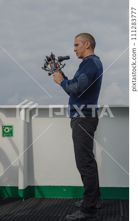 Seaman with sextant on navigational bridge 111283777