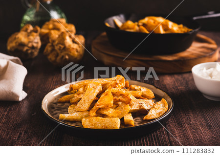 Pieces of celery root fried with paprika on a plate on the table Pieces of celery root fried with paprika on a plate on the table 111283832