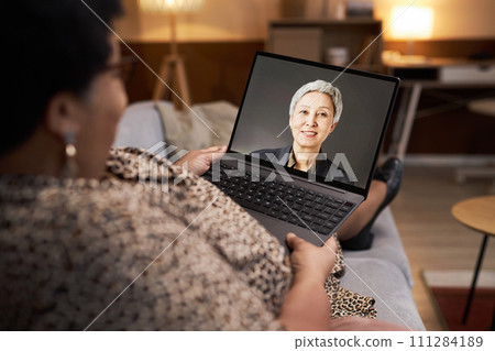 Over shoulder view of Black senior woman talking to specialist in online consultation via video chat copy space 111284189