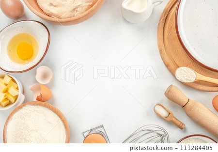 Baking Cooking Ingredients Flour, eggs, sugar, spices, and a whisk on the kitchen table. top view. copy space 111284405
