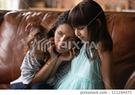 Compassionate little hispanic daughter sit on sofa comfort upset mum Compassionate little hispanic daughter sit on sofa comfort upset mum 111284475