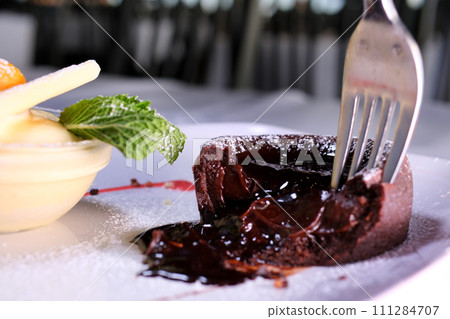 chocolate fondant on a white plate with dark chocolate ice cream strawberries drops of syrup beautiful serving in an expensive restaurant dessert food 111284707