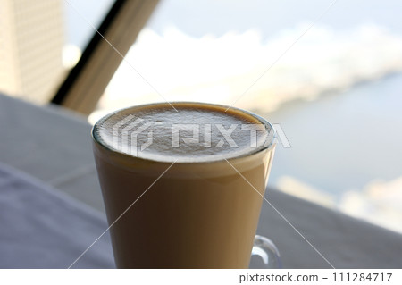 Milk coffee in glass cup and spoon on grey table Milk coffee in glass cup and spoon on grey table 111284717