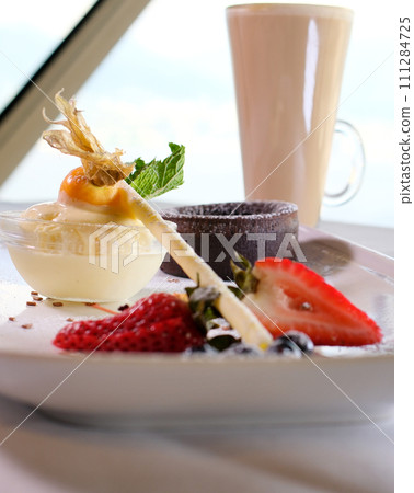 chocolate fondant on a white plate with dark chocolate ice cream strawberries drops of syrup beautiful serving in an expensive restaurant dessert food 111284725