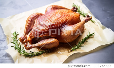 Roast duck adorned with spices and herbs, elegantly presented on parchment 111284882