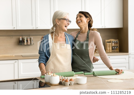 Happy excited mature mom and adult daughter woman wearing aprons 111285219