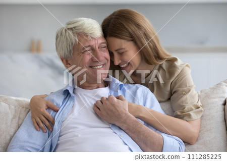 Loving adult daughter cuddling her grey haired father Loving adult daughter cuddling her grey haired father 111285225
