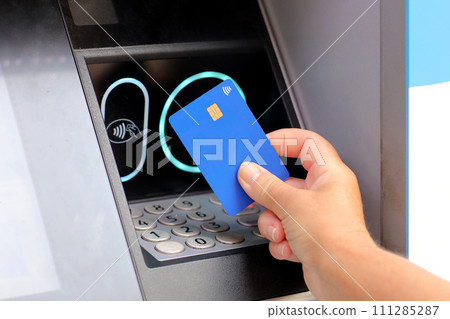 female hand with card by ATM. hand with credit card withdrawing money from ATM using NFC contactless wifi system. Wireless authentication and data transmission security in finance and banking. female hand with card by ATM. hand with credit card withdrawing money from ATM using NFC contactless wifi system. Wireless authentication and data transmission security in finance and banking. 111285287