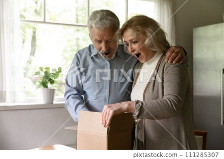 Excited senior couple unboxing postal delivery receive great gift surprise Excited senior couple unboxing postal delivery receive great gift surprise 111285307