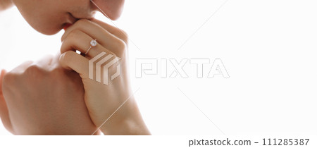 She told him yes. Close-up of a young man kissing his wife's hand with gold ring while making a marriage proposal. Engagement of a young couple in love. The concept of love and togetherness. 111285387