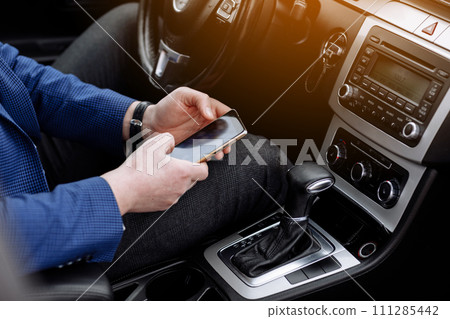 businessman in suit working with project statistics, graph and diagram on phone screen, entrepreneur accountant analysing financial data while sitting in modern car. Male going to workplace by car businessman in suit working with project statistics, graph and diagram on phone screen, entrepreneur accountant analysing financial data while sitting in modern car. Male going to workplace by car 111285442