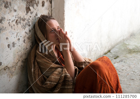 A girl in poor clothes sits on the ground A girl in poor clothes sits on the ground 111285700