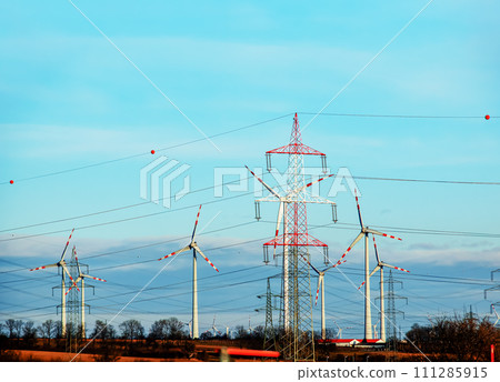 Wind farm park and high voltage towers next to a road in Austria in sunny weather. Wind farm park and high voltage towers next to a road in Austria in sunny weather. 111285915