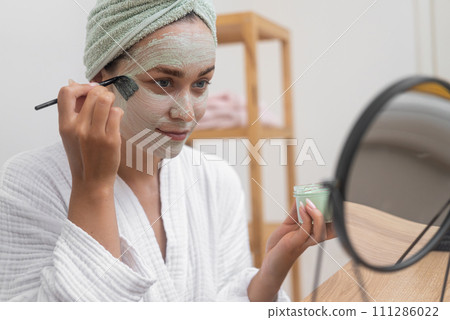 Post-Bath Luxury: Towel-draped, she applies a facial mask for anti-aging, moisture, and perfecting her skin. Post-Bath Luxury: Towel-draped, she applies a facial mask for anti-aging, moisture, and perfecting her skin. 111286022