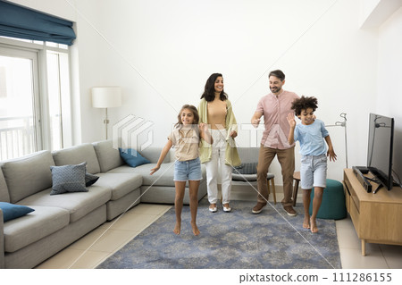 Cheerful parents and two preteen kids dancing in flat 111286155