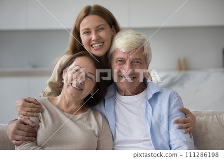 Portrait of adult daughter posing for camera with mature parents 111286198