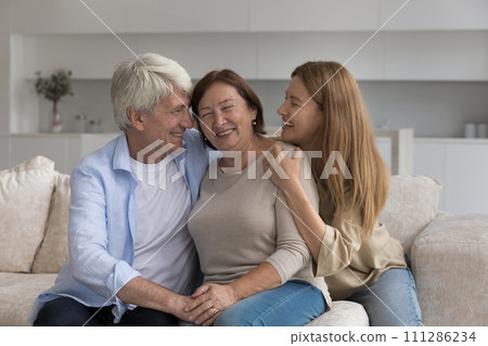 Loving multigenerational family cuddling sitting on couch 111286234