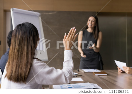 Back view of young employee woman raising hand, asking question Back view of young employee woman raising hand, asking question 111286251