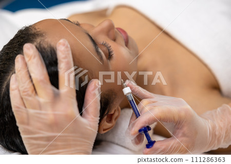 Close up of female face and hands with syringe 111286363