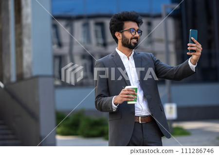 Elegant hindu young man with a phone in hands Elegant hindu young man with a phone in hands 111286746