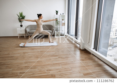 Caucasian woman spread legs wide straightening arms in different directions. 111286762