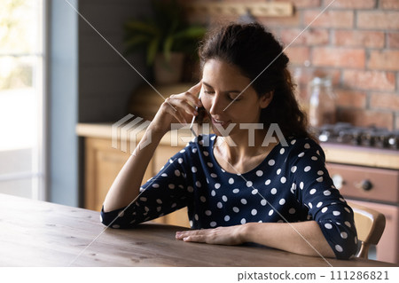 Smiling young woman making phone call, sitting at wooden table Smiling young woman making phone call, sitting at wooden table 111286821