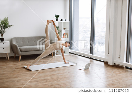 Yogini improving body strength while holding Side Plank Pose with lifted leg. 111287035