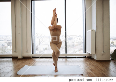 Caucasian woman in sport clothes performing advanced yoga pose. 111287066