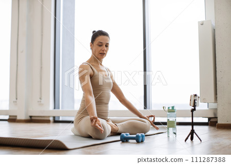 Professional female trainer recording video using tripod and smartphone. 111287388