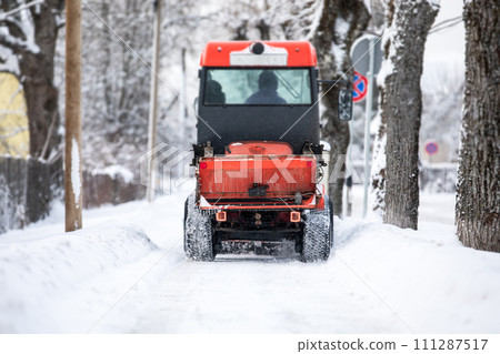 Snow plow shoveling snow on the sidewalk, harsh winter, view from back Snow plow shoveling snow on the sidewalk, harsh winter, view from back 111287517