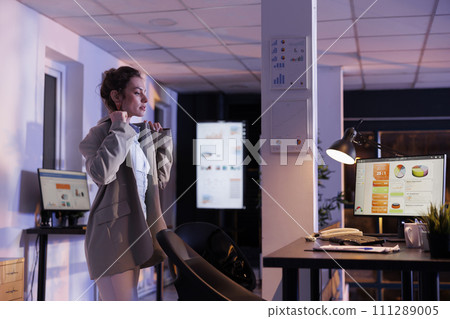 Company worker preparing to leave startup office late at night after finishing financial growth report. Businesswoman working overhours at marketing strategy in startup office. Business concept Company worker preparing to leave startup office late at night after finishing financial growth report. Businesswoman working overhours at marketing strategy in startup office. Business concept 111289005