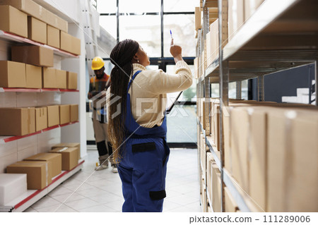 African american storehouse manager checking parcels maintenance and planning stock supply chain logistics. Warehouse supervisor standing near cardboard boxes shelf and looking upwards African american storehouse manager checking parcels maintenance and planning stock supply chain logistics. Warehouse supervisor standing near cardboard boxes shelf and looking upwards 111289006